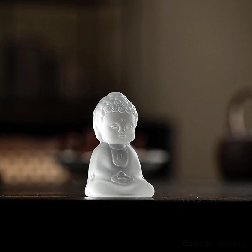 Frosted glass Buddha statue on dark wooden tea table creating peaceful meditation space