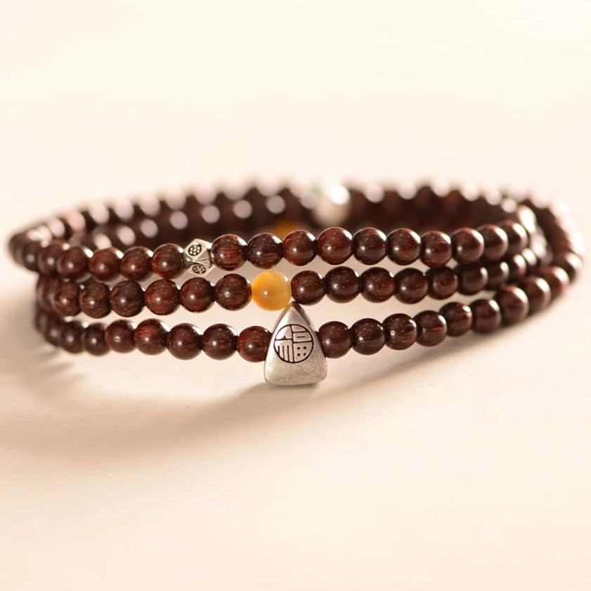 Fu character protection bracelet flat lay display showing polished wooden sandalwood beads with silver charm on white background
