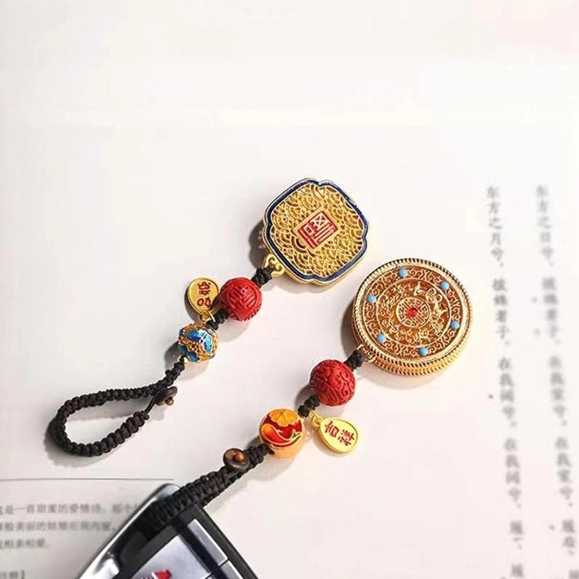 Buddhist Fu keychain pendant showing enamel work with jade-like color and metal filigree frame design