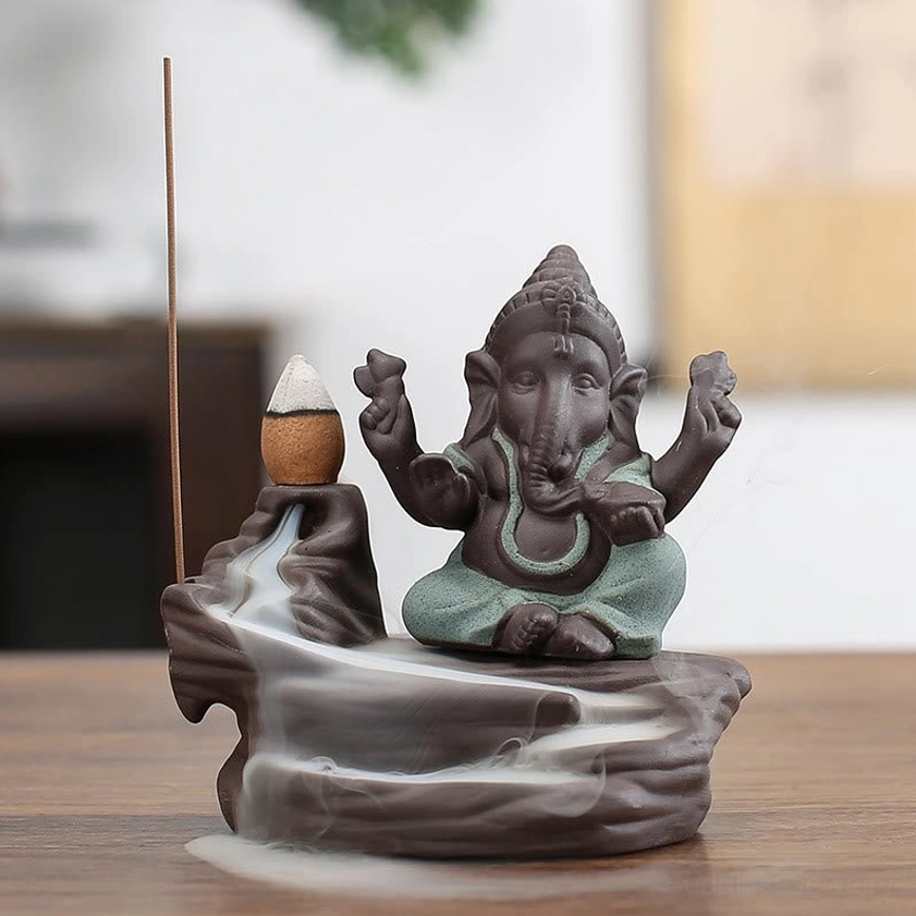 Green Ganesha deity backflow incense burner on purple clay base with flowing aromatic smoke, front presentation