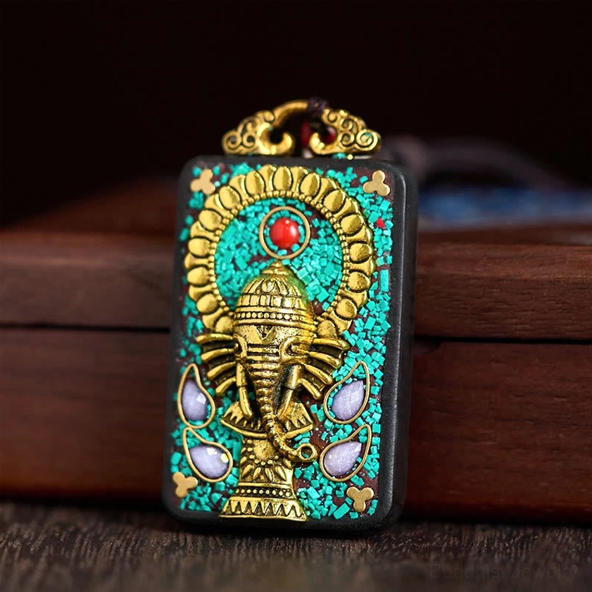 Close-up detail of Ganesha elephant pendant with turquoise inlay and gemstone accent on dark wood