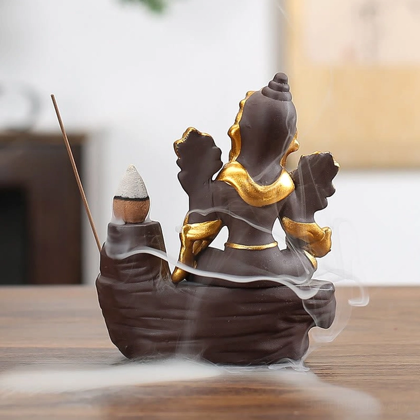 Rear view of Ganesha backflow incense burner showing gold decorative details and smoke flowing from back, purple clay base