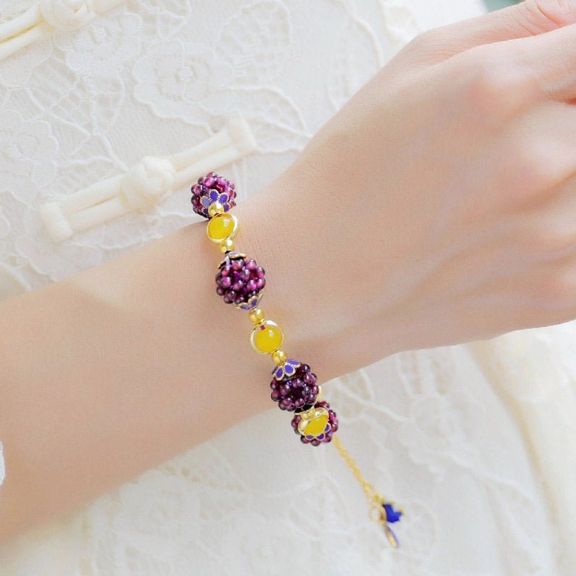 Garnet amethyst healing bracelet worn on wrist with gradient beads and enamel accents against white fabric
