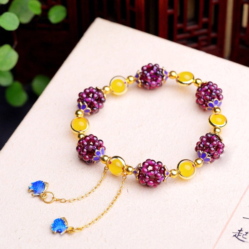 Garnet amethyst Buddhist bracelet with extender chain and blue enamel charms on book surface