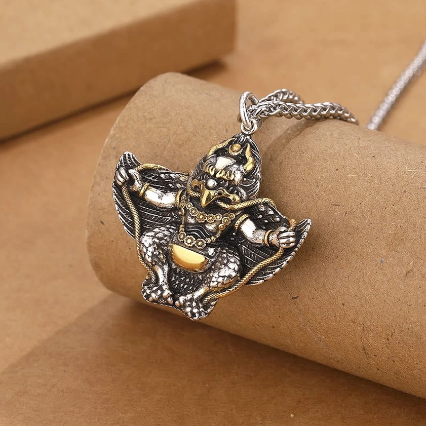Vintage mixed metal Garuda Bird pendant displayed on kraft paper showing intricate carving details