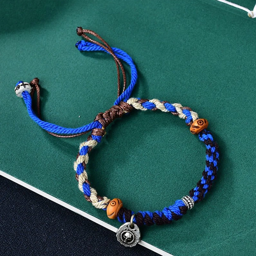 Blue Garuda protection string bracelet with hand-woven blue-brown-cream braided rope, wooden beads, and metal charm