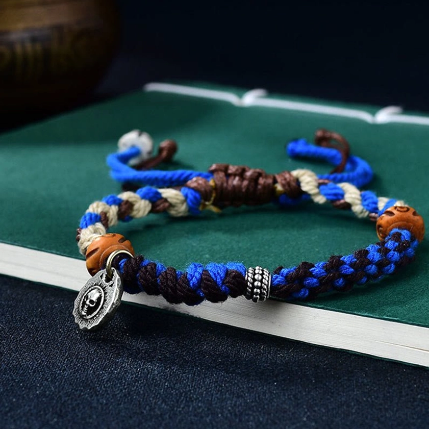 Garuda protection bracelet close-up detail showing hand-woven cord, bone beads, and Tibetan silver charm pendant