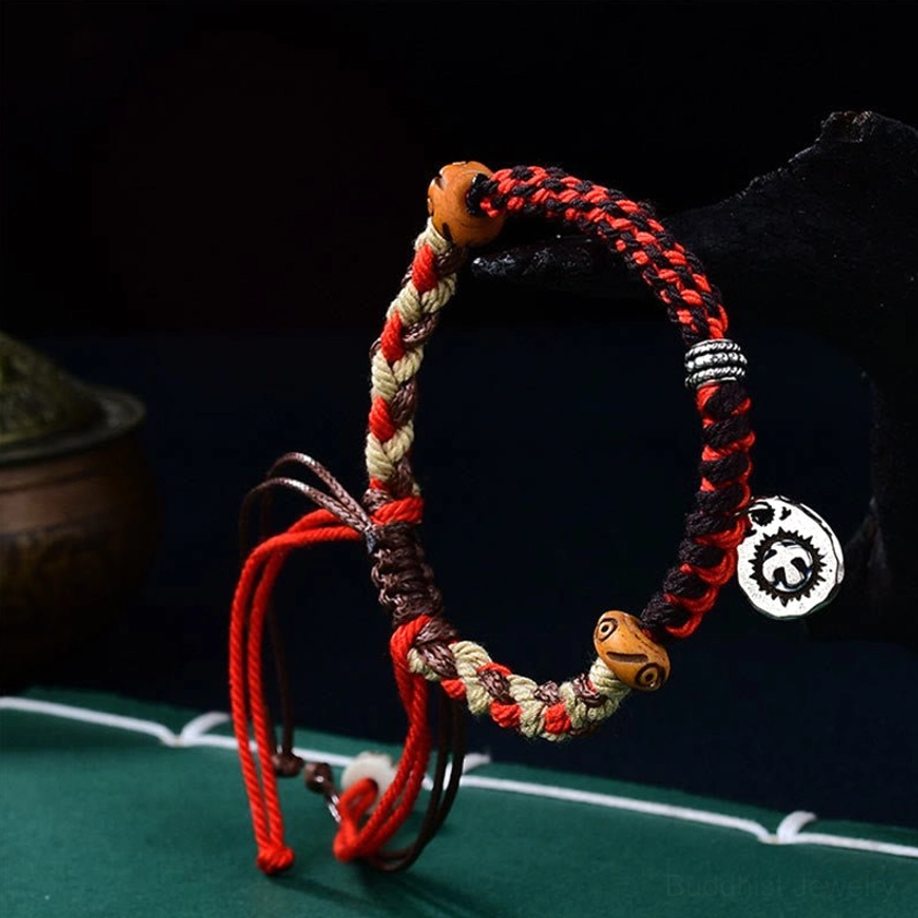 Buddhist Garuda luck bracelet front view with mixed-color woven cord, carved wooden beads, metal pendant, and adjustable tie strings