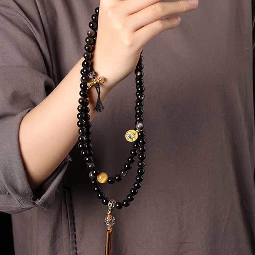 Close-up of Silver Sheen Obsidian Garuda necklace worn around neck with golden accent beads and pendant