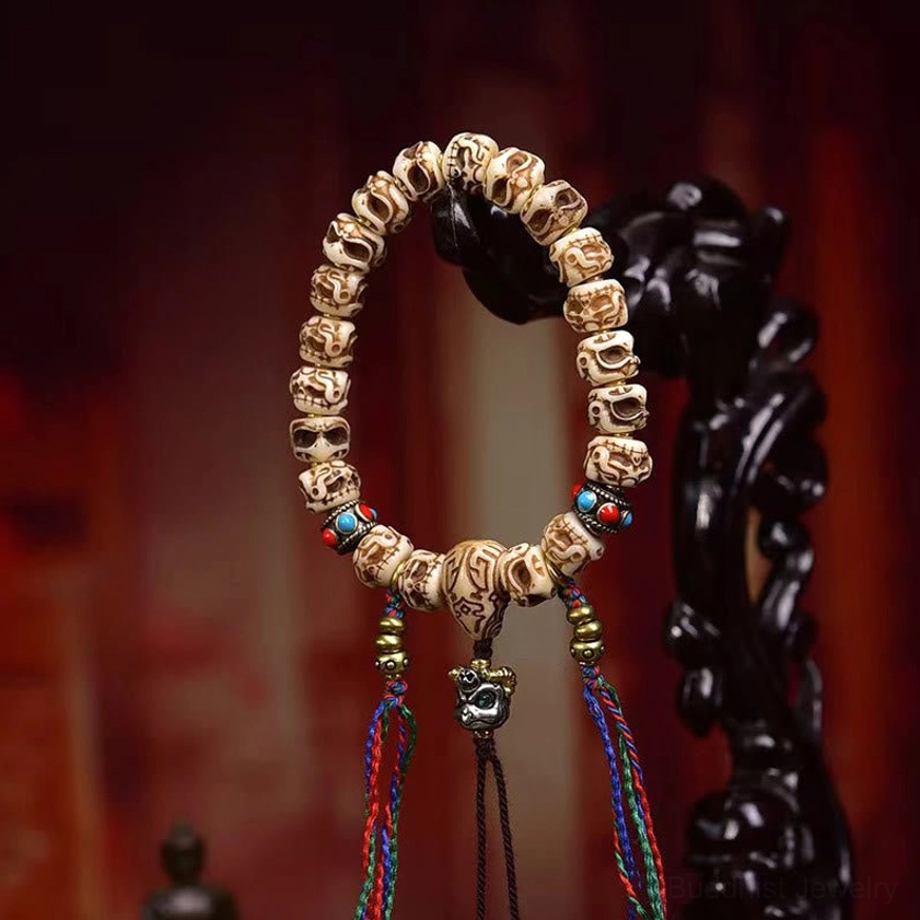 Handcrafted camel bone Garuda tassel bracelet showing dual tassels and metal Garuda charm on ceremonial background