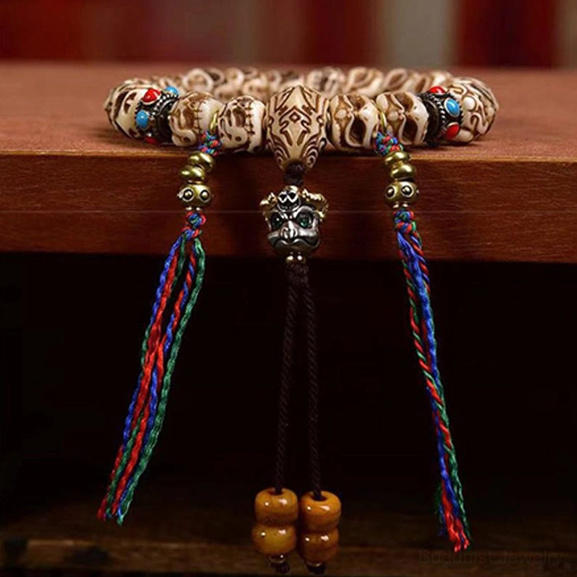Close-up detail of carved Garuda camel bone bead with multi-color tassels and wooden pendant accents