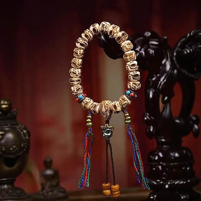 Camel bone Garuda bracelet with dual colorful tassels on red Buddhist background with decorative carvings