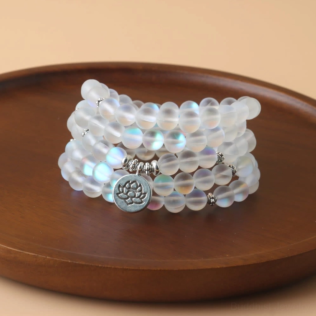 108 glitter stone mala beads bracelet with lotus charm displayed on wooden tray, iridescent frosted beads with silver spacers and engraved lotus pendant