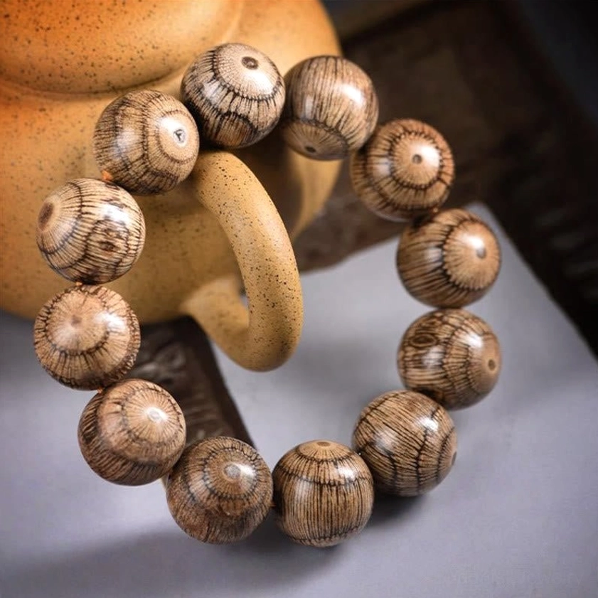 Angled side view of gnetum wood beaded bracelet showing natural wood grain texture and soft studio lighting