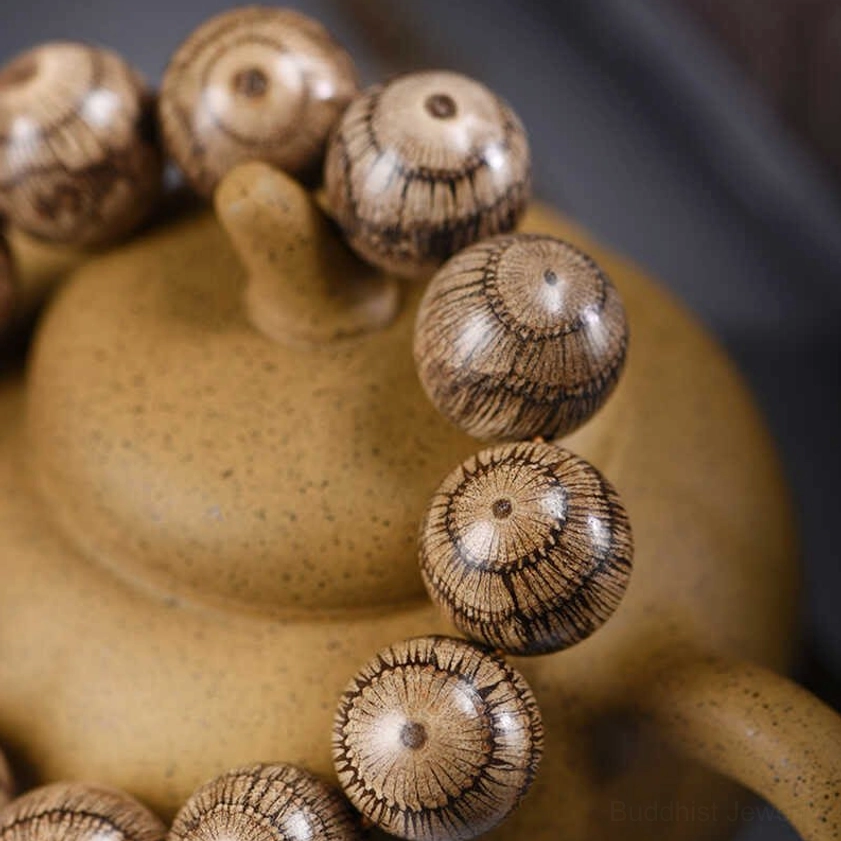 Overhead detail view of gnetum wood Buddhist bracelet showing intricate radial wood grain pattern on each bead