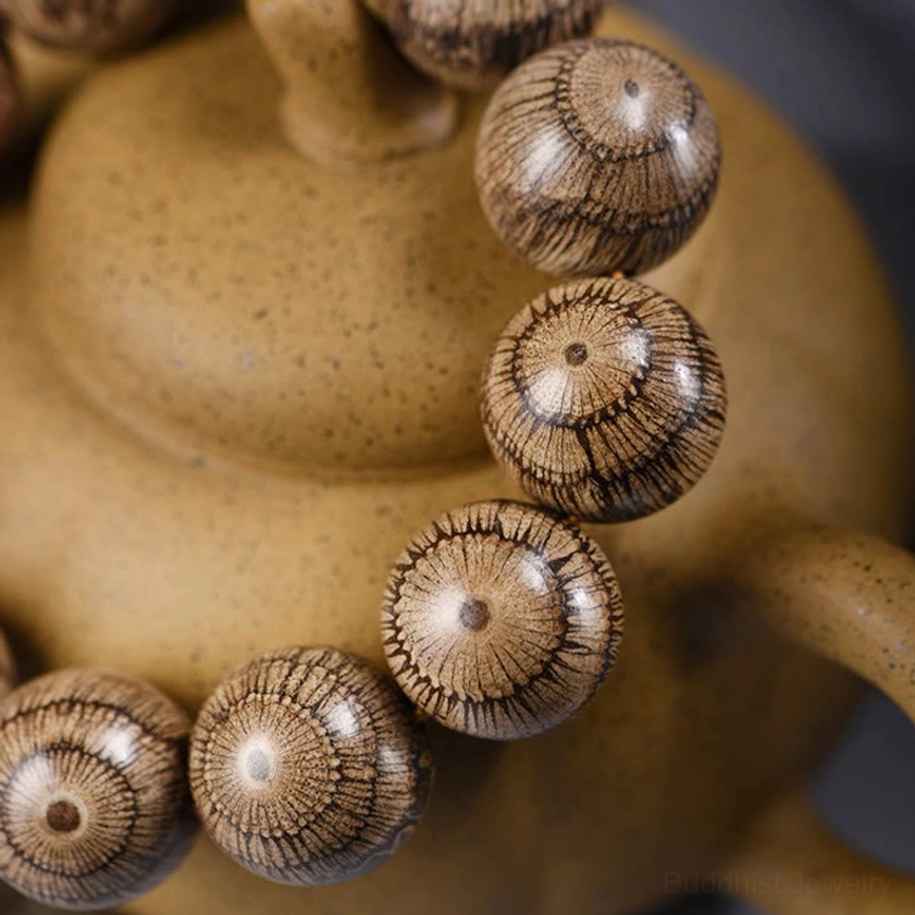 Single gnetum wood bead close-up displaying authentic radial wood texture and natural craftsmanship of Buddhist protection bracelet