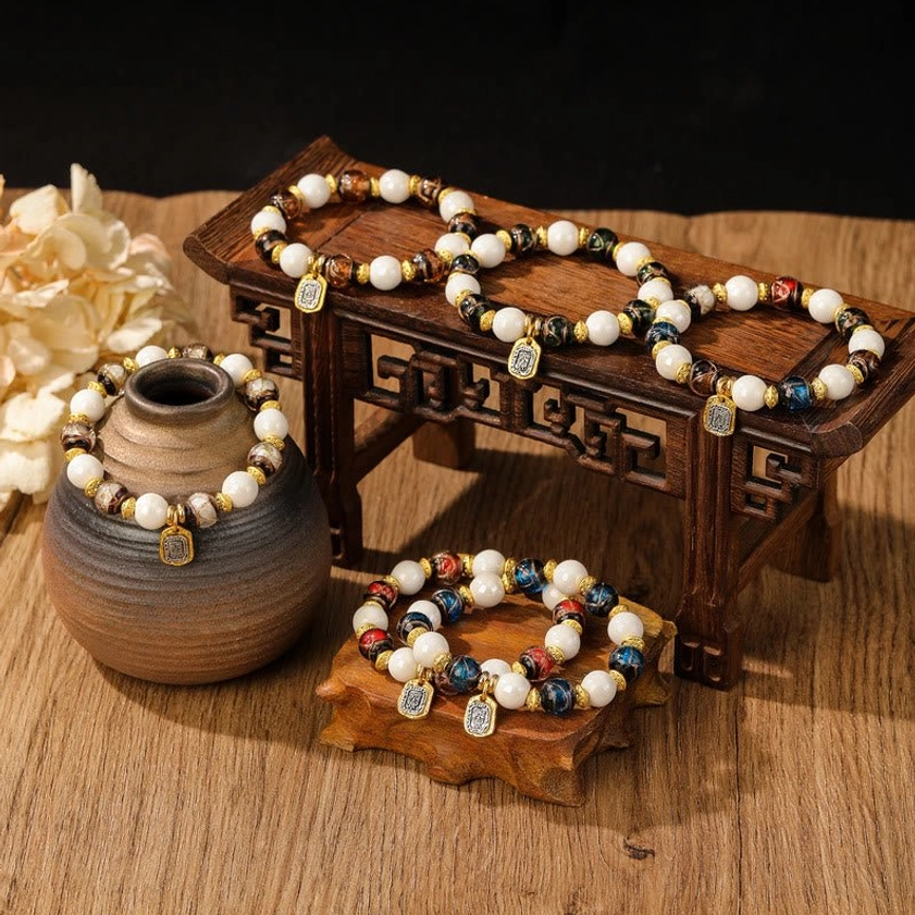 Multiple Goddess of Wealth charm bracelets in various colorways arranged on wooden display blocks with dried flowers
