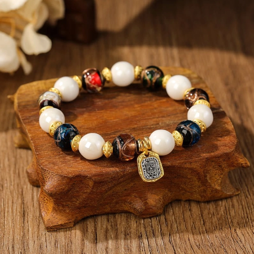 Handcrafted Goddess of Wealth bracelet showcasing dark blue and brown patterned liuli glass beads with white porcelain accents