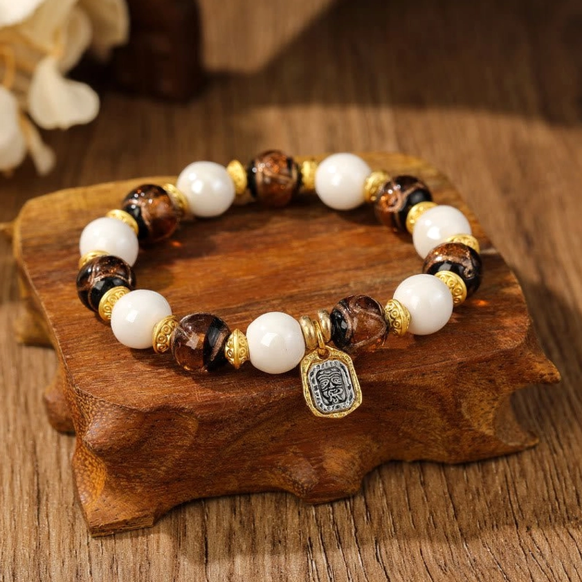 Spiritual Goddess of Wealth bracelet featuring dark striped brown ceramic beads, white porcelain beads, and vintage-style metal charm