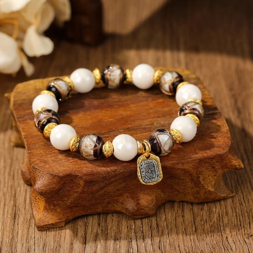 Goddess of Wealth bracelet detail with marbled grey-brown ceramic beads, creamy white beads, and ornate metal pendant