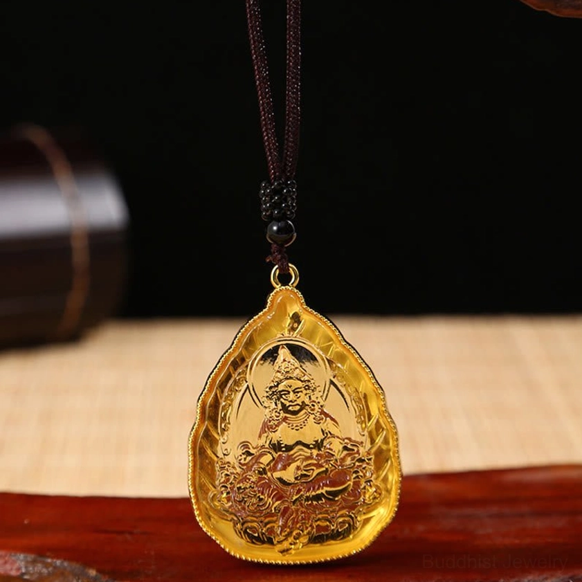 Golden Buddhist Buddha crystal pendant necklace close-up showing embossed seated Buddha figure with gold metal rim and dark brown beaded rope on wooden base