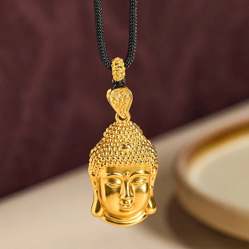 Close-up of polished gold Buddha head pendant with simple elegant design