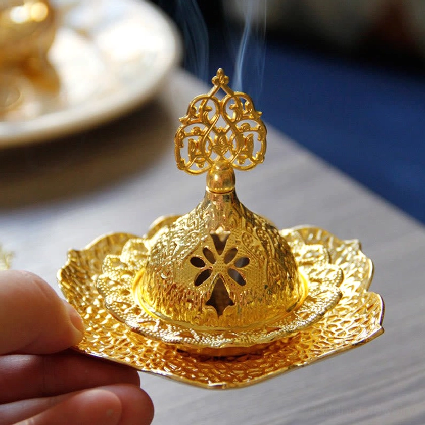 Handcrafted gold alloy incense holder with ornate top finial and embossed metal texture, side view detail