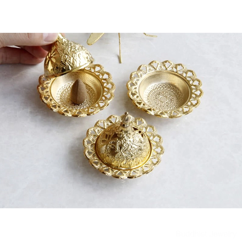 Gold handcrafted incense burner with ornamental design and cone incense for meditation and spiritual practice