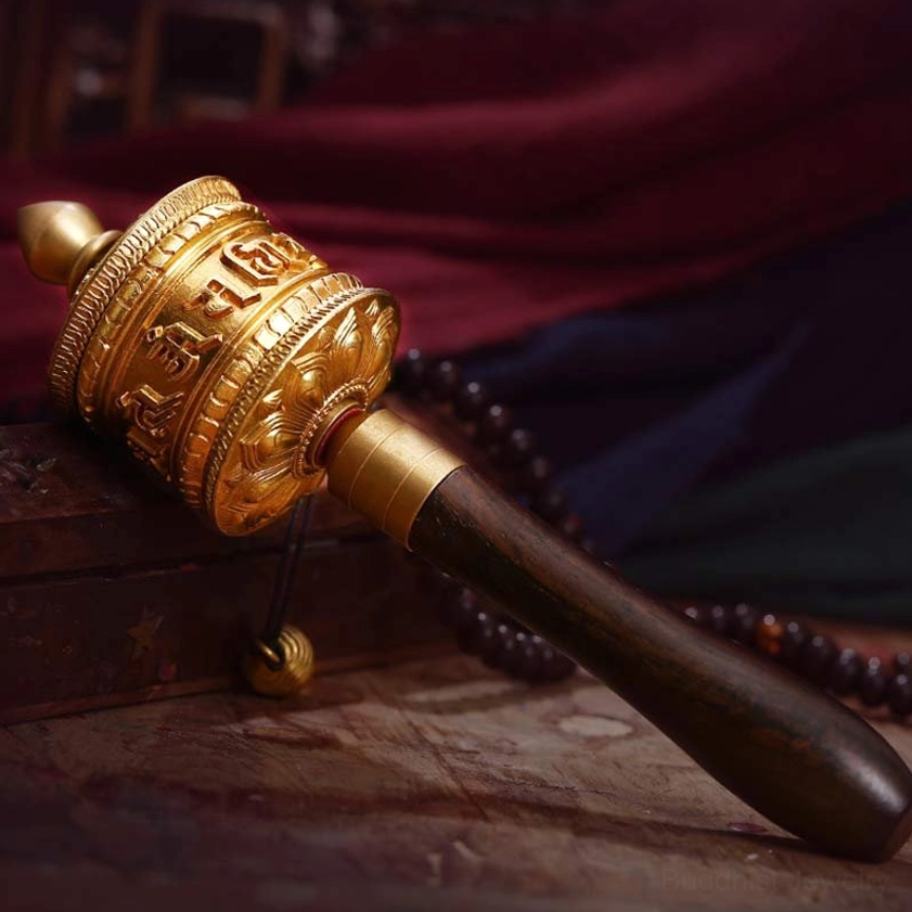 Gold-toned Buddhist prayer wheel meditation tool with embossed mantras and brass accents, traditional wooden grip