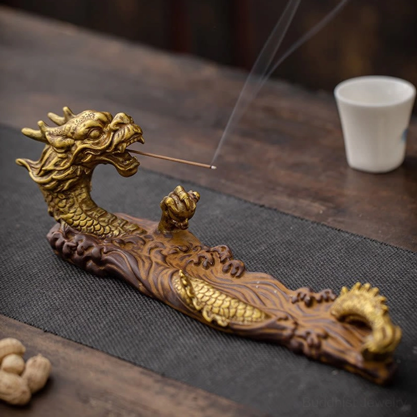 Gold gilded dragon ceramic incense burner with ornate wave-carved base, displayed on wooden tea table from high side angle