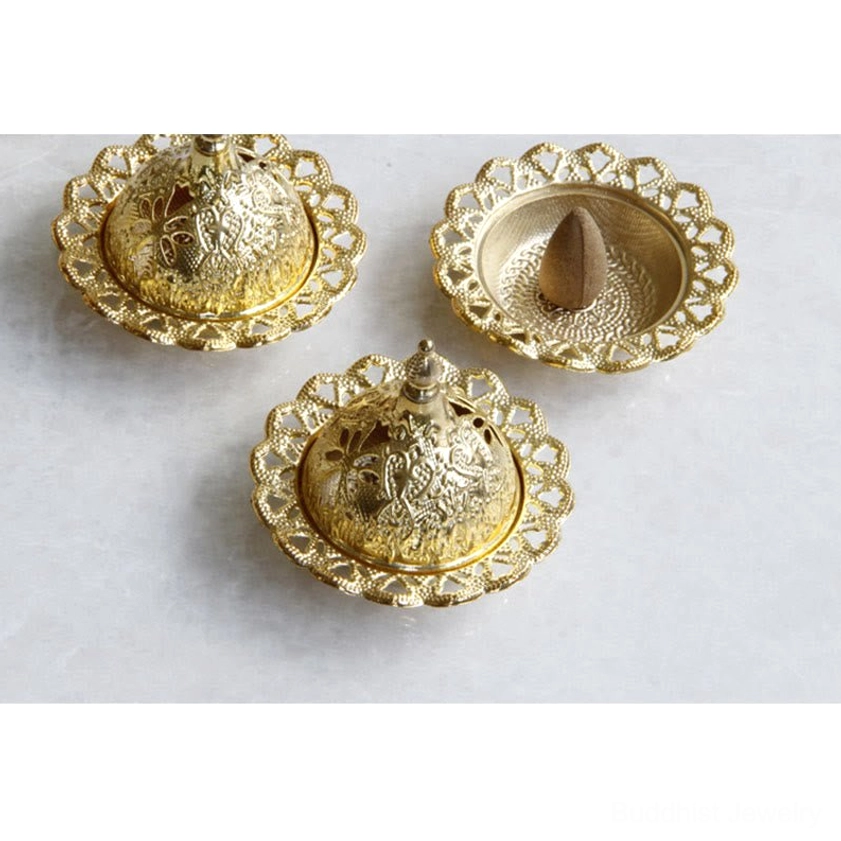 Three gold Buddhist incense burners with hollowed floral trays and one with cone incense burning
