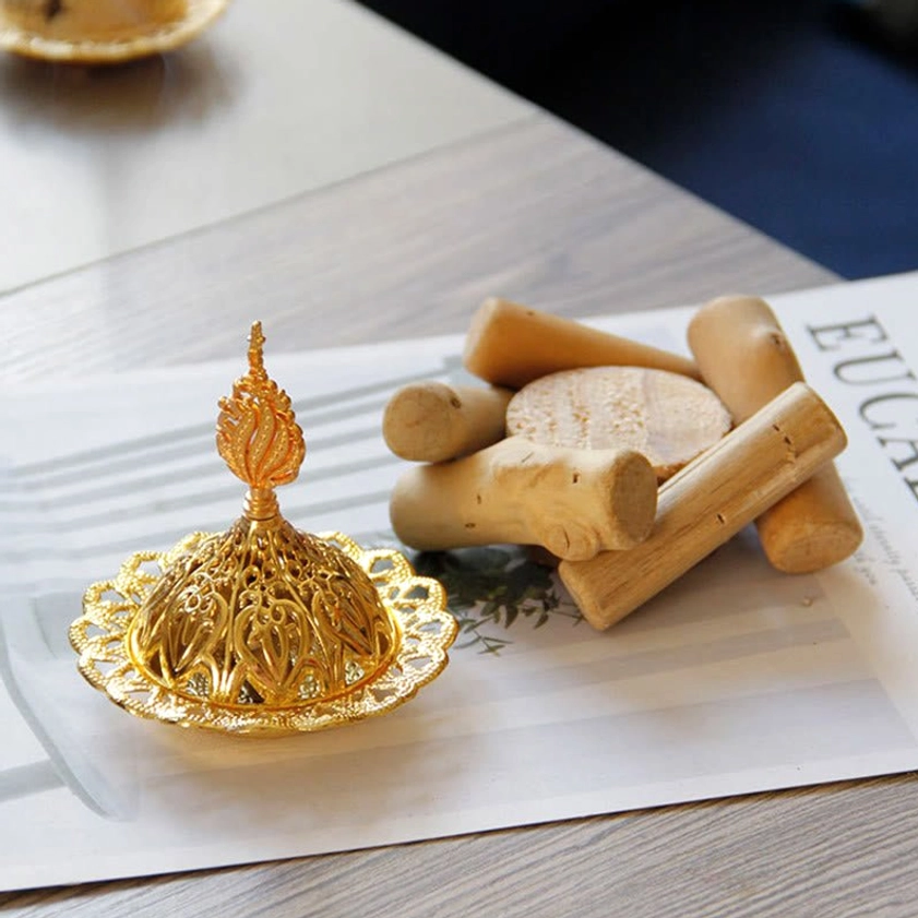 Gold incense burner components - metal carved lid and tray separated from natural wooden coaster - oblique top view