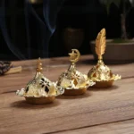 Gold brass incense burner set with three interchangeable finials on wooden desk with incense smoke rising