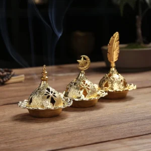 Gold brass incense burner set with three interchangeable finials on wooden desk with incense smoke rising