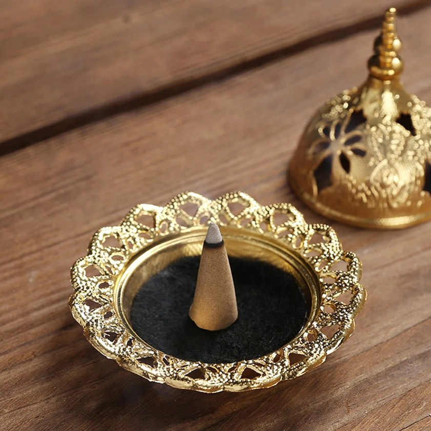 Gold incense burner with cone incense inside showing interior design and black lining detail