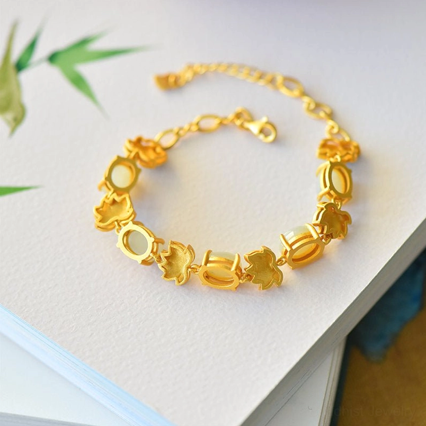 Gold-toned lotus charm links Buddhist bracelet with spring clasp displayed on a book flat lay