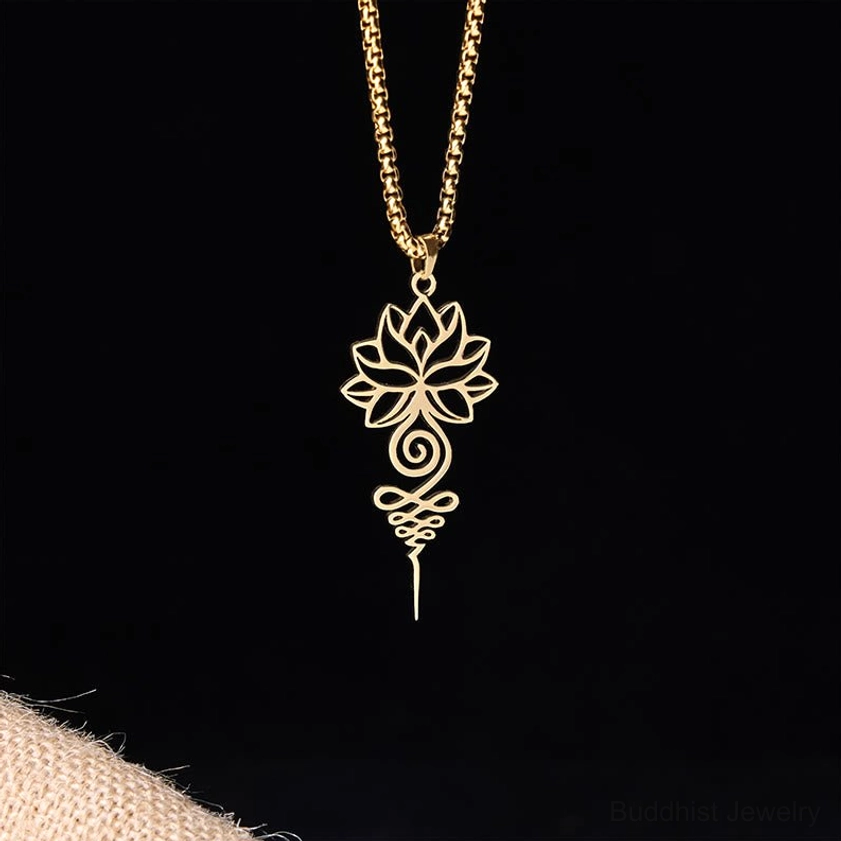 Gold lotus unalome spiritual necklace with polished metal finish on black background with beige knit cuff accessory