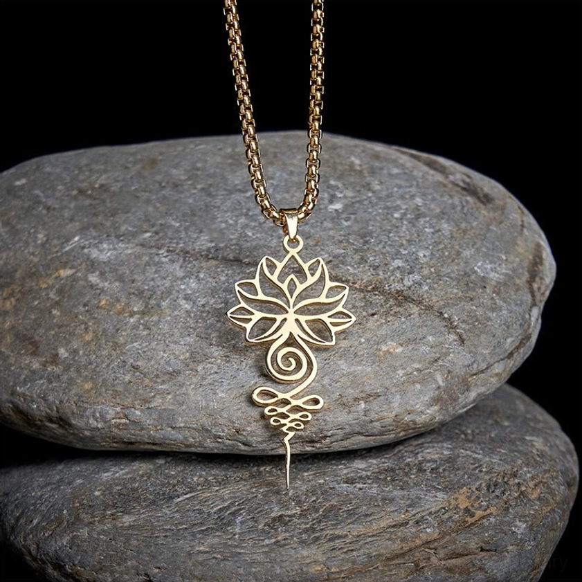 Gold lotus unalome chakra necklace pendant on stacked grey stones, showing polished gold-tone stainless steel finish