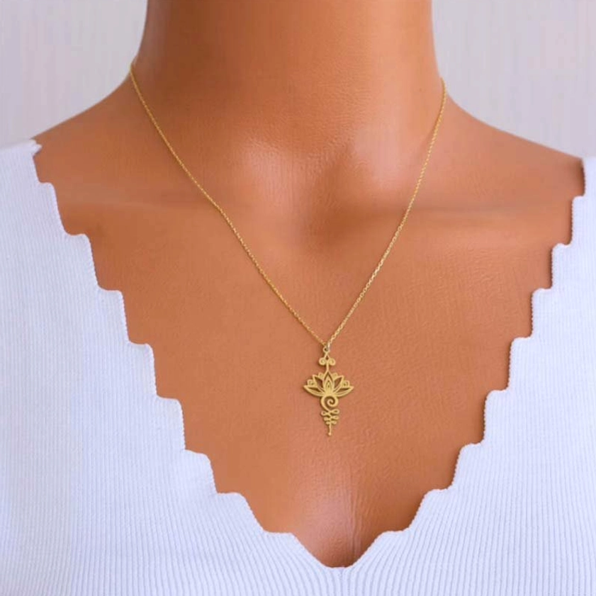 Woman wearing delicate gold lotus unalome necklace with thin chain, worn on mannequin with white scalloped top showing styling