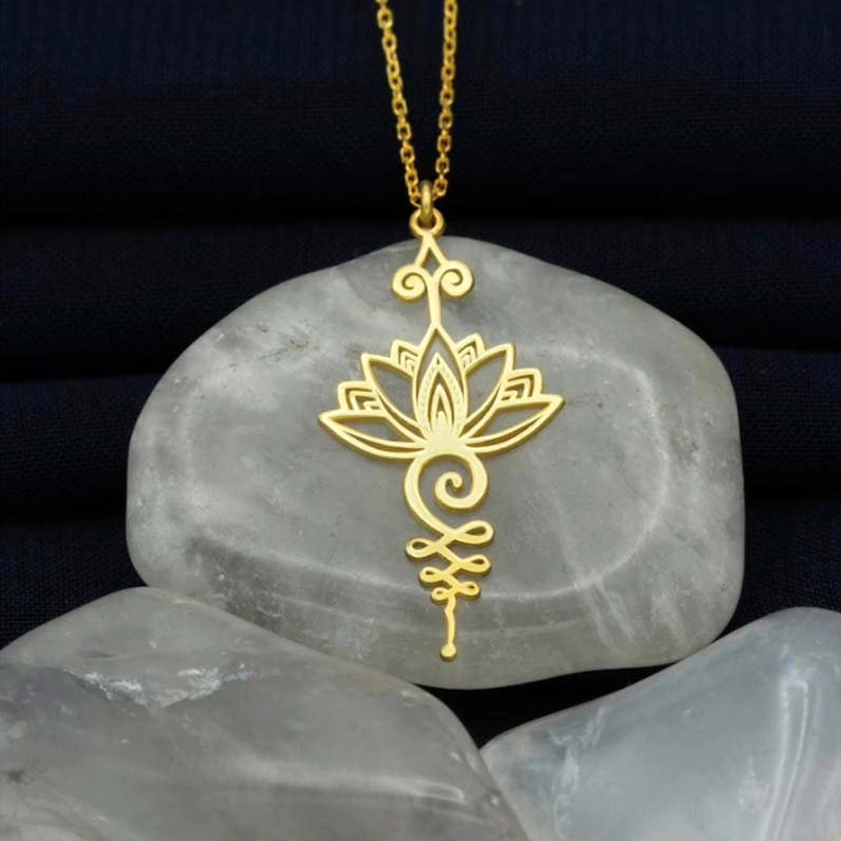Gold lotus unalome pendant necklace with intricate hollow carved design on dark fabric, representing enlightenment and prosperity