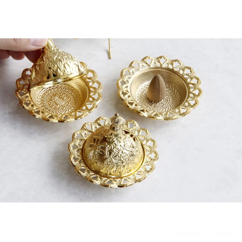 Hand lifting ornamental gold incense burner lid showing interior tray with cone incense