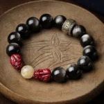 Gold sheen obsidian pixiu cinnabar Buddhist protection bracelet with om mani padme hum mantra spacer on wooden tray