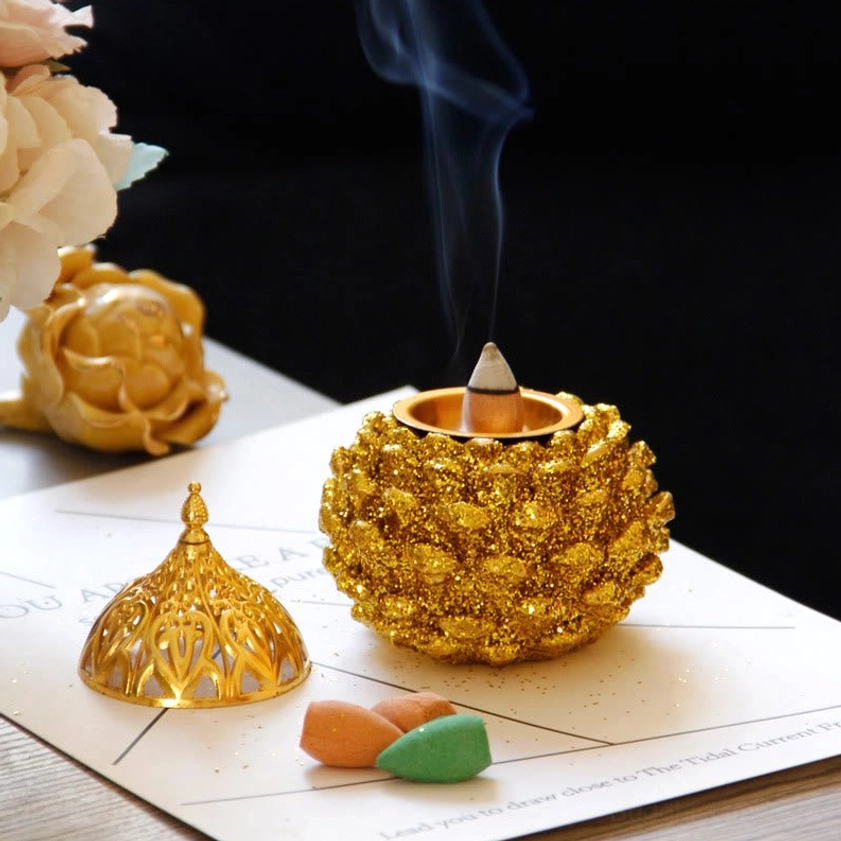 Close-up detail of gold pine cone incense burner's intricate carved pattern and glittery surface texture