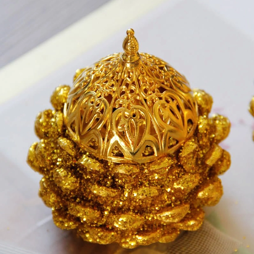 Closed gold pine cone incense burner with ornate hollow carved dome lid, side perspective