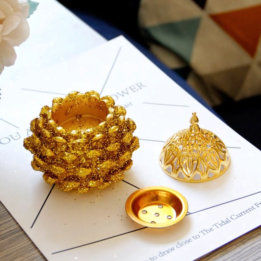 Disassembled components of incense burner showing removable vent tray, dome lid, and glittery golden body