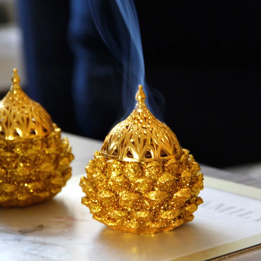 Gold Pine Cone Incense Burner with glittery golden finish and ornate carved dome lid, three-quarter tabletop view