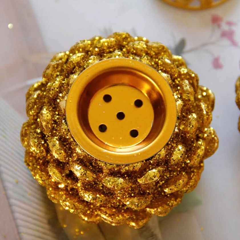 Top-down close-up view of gold incense burner showing 5-hole ventilation system and glittery pine cone body