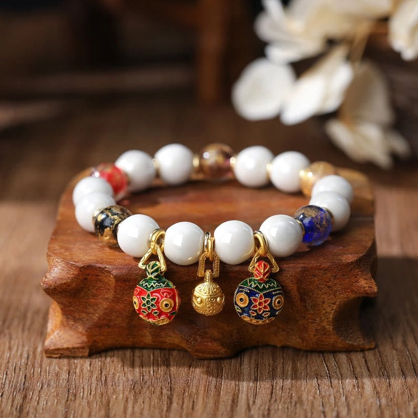 Single gold Pixiu family bracelet with mixed accent beads and enamel pendants on light wooden table