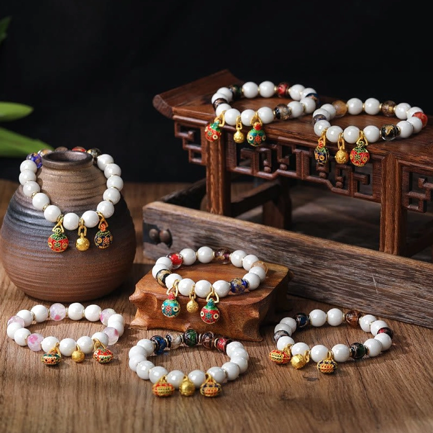 Gold Pixiu Family prosperity bracelet with multicolored liuli glass beads and enamel charms displayed on wooden table
