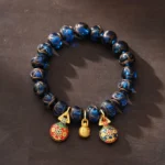 Gold Pixiu wealth bracelet with blue liuli glass beads and three protective prosperity charms - overhead view